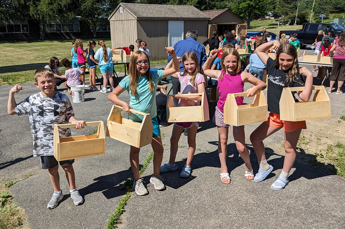 Green Meadow students holding wooden toolboxes